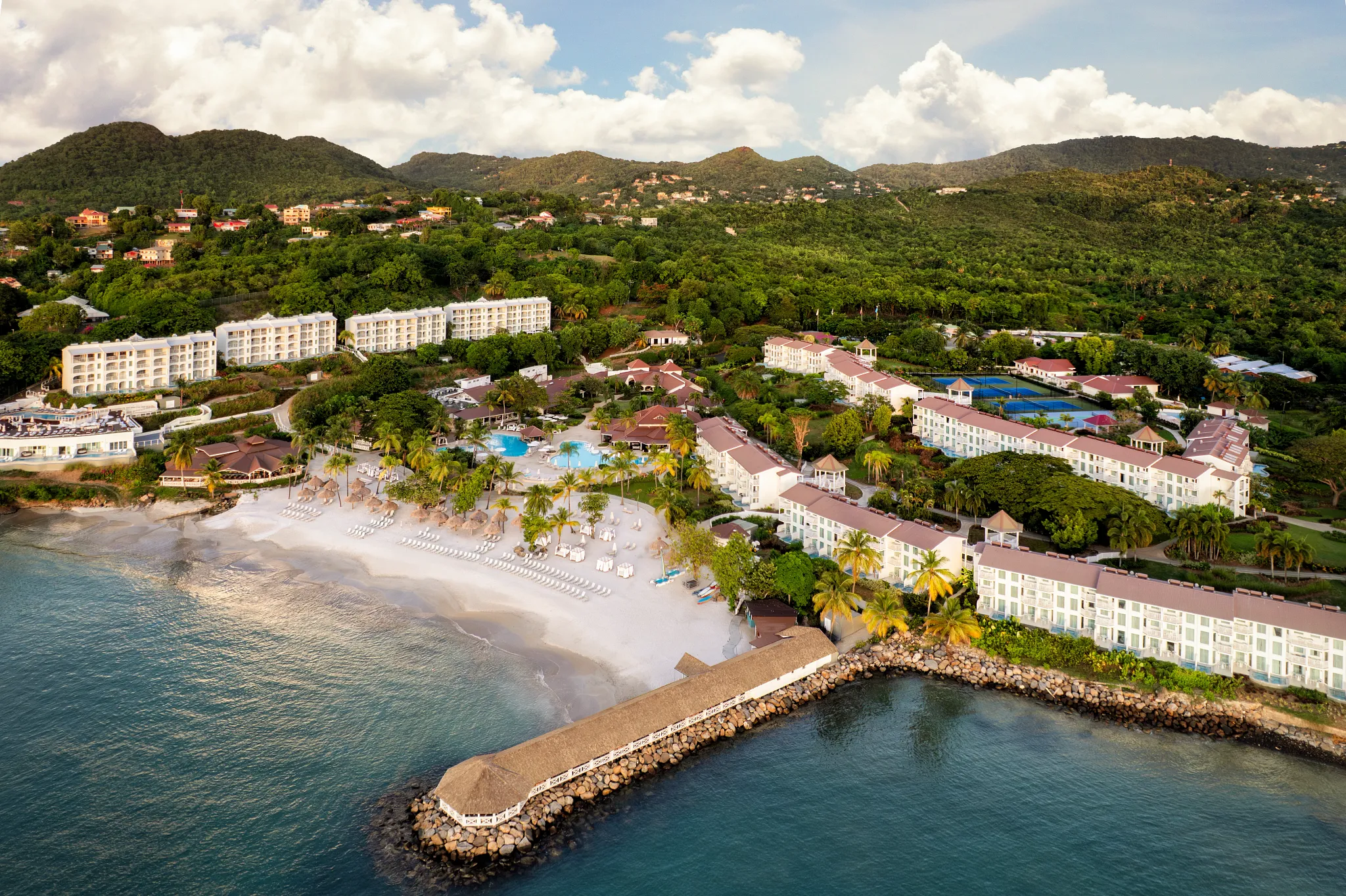 Wide aerial view of Secrets St. Lucia Resort & Spa with coastline and surrounding hills.
